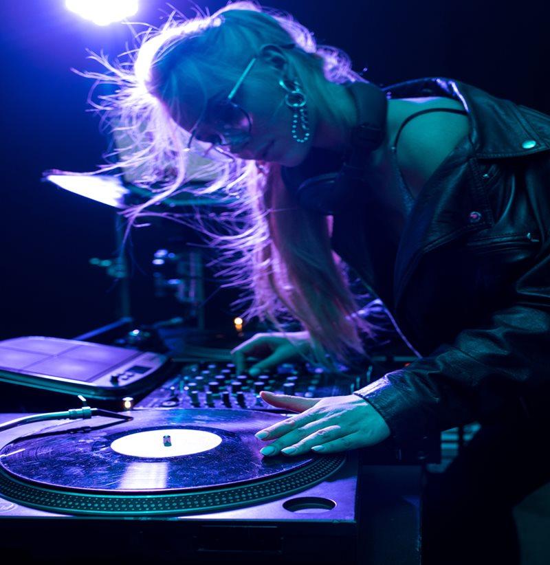 beautiful blonde dj girl touching vinyl record in nightclub