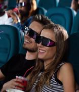 Movieholics. Gorgeous young woman smiling happily while cuddling with her handsome boyfriend during movies at the cinema